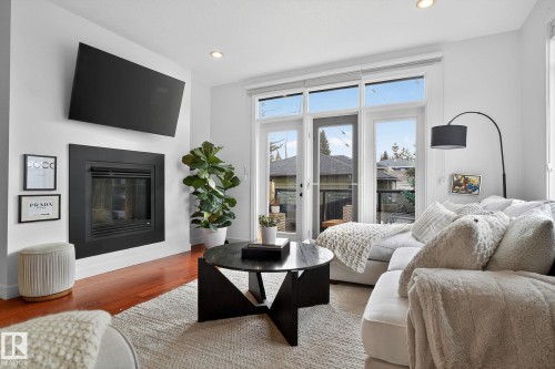 Living area with a glass covered fireplace, hardwood / wood-style flooring, and recessed lighting - 1 9561 143 Street Nw, Edmonton, AB - Indoor Photo Showing Living Room With Fireplace