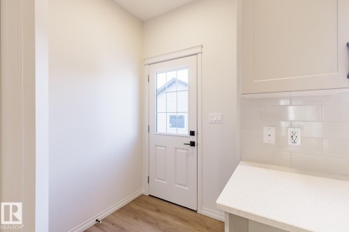 Doorway with wood finished floors and baseboards - 90 Dansereau Way N, Beaumont, AB - Indoor Photo Showing Other Room