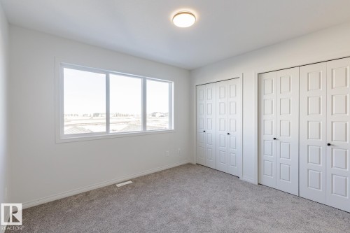 Unfurnished bedroom featuring multiple closets and carpet floors - 90 Dansereau Way N, Beaumont, AB - Indoor