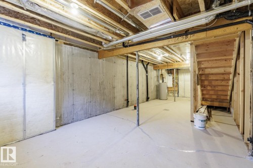 Unfinished basement featuring water heater - 90 Dansereau Way N, Beaumont, AB - Indoor Photo Showing Basement