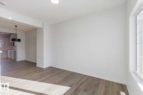 Unfurnished living room with light wood-type flooring and baseboards - 90 Dansereau Way N, Beaumont, AB - Indoor Photo Showing Other Room