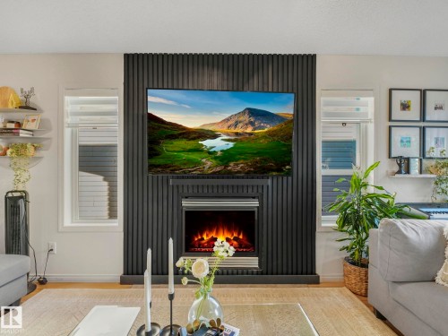 Living area featuring a lit fireplace and wood finished floors - 3239 21 Street, Edmonton, AB - Indoor With Fireplace