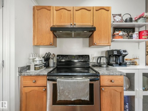 Kitchen featuring electric range, ventilation hood, open shelves, wood finish cabinetry, and light stone countertops - 3239 21 Street, Edmonton, AB - Indoor Photo Showing Kitchen