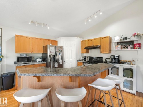 Kitchen with light wood finished floors, a kitchen breakfast bar, and stainless steel appliances - 3239 21 Street, Edmonton, AB - Indoor Photo Showing Kitchen