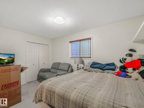 Carpeted bedroom featuring a textured ceiling and a closet - 3239 21 Street, Edmonton, AB - Indoor Photo Showing Bedroom