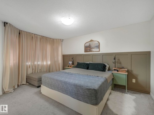Bedroom featuring a decorative wall, a textured ceiling, wainscoting, and carpet flooring - 3239 21 Street, Edmonton, AB - Indoor Photo Showing Bedroom