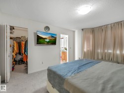 Bedroom featuring a walk in closet, light colored carpet, a textured ceiling, and connected bathroom - 