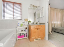 Bathroom featuring vanity, a bath, light carpet, and light tile patterned floors - 