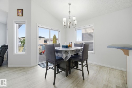 Dining area featuring vaulted ceiling, light wood finished floors, and a chandelier - 3248 22 Street, Edmonton, AB - Indoor Photo Showing Dining Room