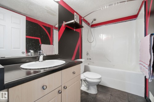 Bathroom with vanity, shower / tub combination, a textured ceiling, and dark tile patterned floors - 3248 22 Street, Edmonton, AB - Indoor Photo Showing Bathroom