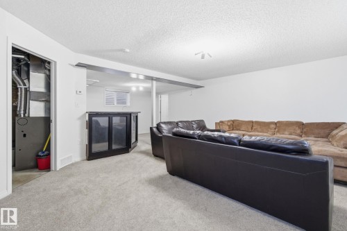 Carpeted living room featuring a textured ceiling and heating unit - 3248 22 Street, Edmonton, AB - Indoor