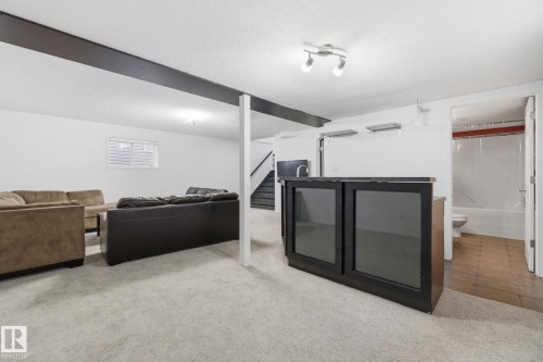 Living room featuring a textured ceiling and light carpet - 3248 22 Street, Edmonton, AB - Indoor Photo Showing Basement