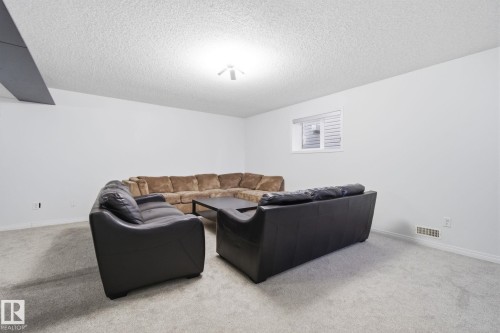 Carpeted living room featuring a textured ceiling - 3248 22 Street, Edmonton, AB - Indoor