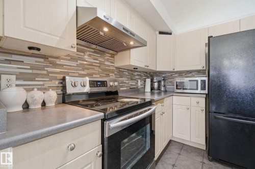 Kitchen featuring stainless steel appliances, light countertops, decorative backsplash, and light tile patterned floors - 3248 22 Street, Edmonton, AB - Indoor Photo Showing Kitchen