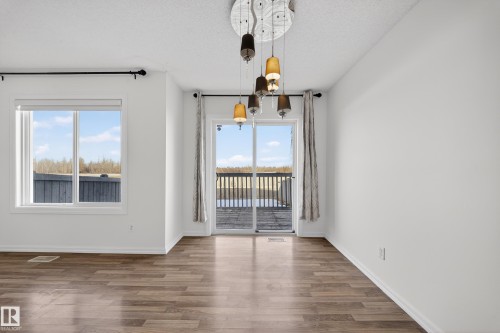 Unfurnished dining area with wood finished floors, a textured ceiling, and hanging lights - 5212 1A Avenue, Edmonton, AB - Indoor Photo Showing Other Room
