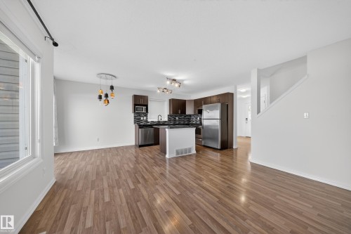 Kitchen featuring open floor plan, dark countertops, stainless steel appliances, backsplash, and dark wood finish cabinets - 5212 1A Avenue, Edmonton, AB - Indoor Photo Showing Kitchen