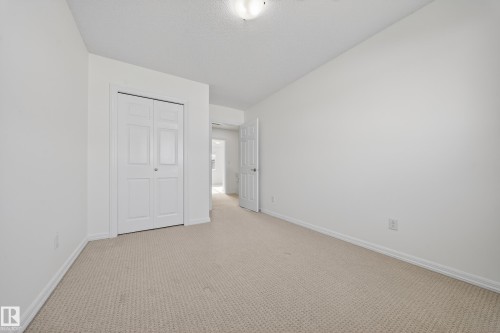 Unfurnished bedroom featuring carpet flooring, a closet, and a textured ceiling - 5212 1A Avenue, Edmonton, AB - Indoor Photo Showing Other Room