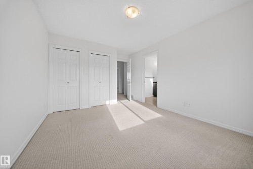 Unfurnished bedroom featuring multiple closets, carpet flooring, and ensuite bathroom - 5212 1A Avenue, Edmonton, AB - Indoor Photo Showing Other Room