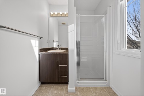 Full bath featuring a stall shower, vanity, and light tile patterned flooring - 5212 1A Avenue, Edmonton, AB - Indoor