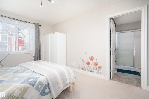 Carpeted bedroom featuring ensuite bath and a textured ceiling - 13 5317 3 Avenue, Edmonton, AB - Indoor Photo Showing Bedroom