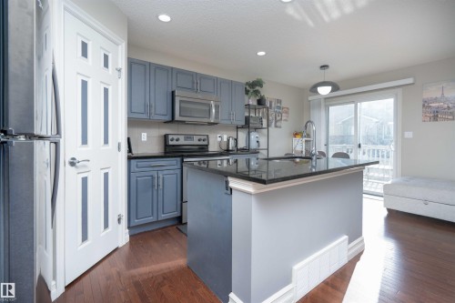 Kitchen featuring stainless steel appliances, dark wood-style flooring, an island with sink, and pendant lighting - 13 5317 3 Avenue, Edmonton, AB - Indoor Photo Showing Kitchen With Stainless Steel Kitchen
