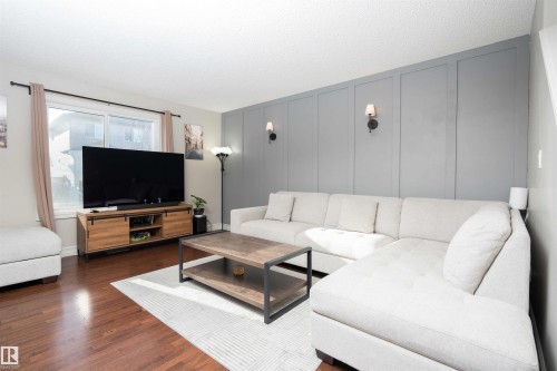 Living room featuring a decorative wall and dark wood-style flooring - 13 5317 3 Avenue, Edmonton, AB - Indoor Photo Showing Living Room