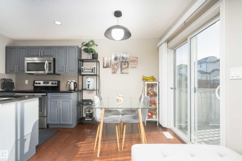 Kitchen featuring gray cabinetry, stainless steel appliances, dark stone counters, dark wood-style floors, and decorative backsplash - 13 5317 3 Avenue, Edmonton, AB - Indoor Photo Showing Kitchen With Stainless Steel Kitchen