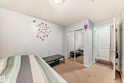 Carpeted bedroom featuring a closet and a textured ceiling - 108 10535 122 Street, Edmonton, AB - Indoor Photo Showing Bedroom
