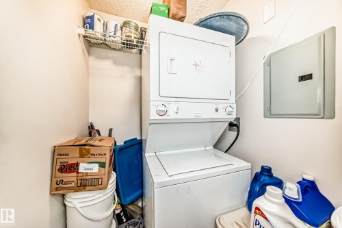 Laundry room with stacked washer and dryer and electric panel - 108 10535 122 Street, Edmonton, AB - Indoor Photo Showing Laundry Room