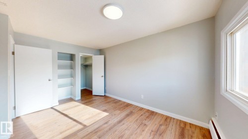 Unfurnished bedroom with baseboard heating, light wood-type flooring, a walk in closet, and multiple windows - 611 2908 116A Avenue, Edmonton, AB - Indoor Photo Showing Other Room