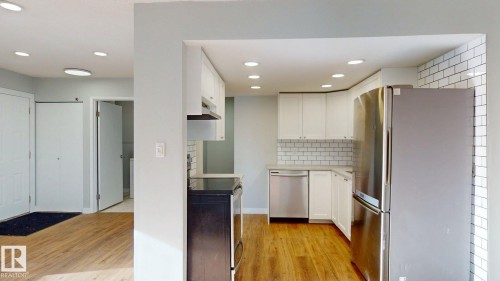 Kitchen featuring stainless steel appliances, white cabinetry, light wood finished floors, recessed lighting, and light stone counters - 611 2908 116A Avenue, Edmonton, AB - Indoor Photo Showing Kitchen