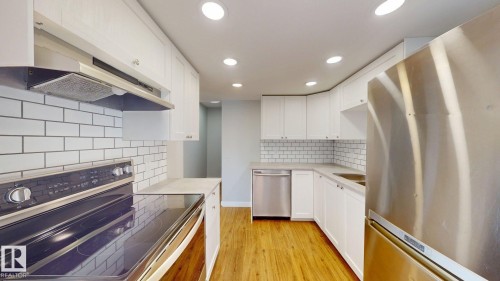 Kitchen with stainless steel appliances, white cabinets, light wood-style flooring, recessed lighting, and tasteful backsplash - 611 2908 116A Avenue, Edmonton, AB - Indoor Photo Showing Kitchen With Stainless Steel Kitchen With Upgraded Kitchen