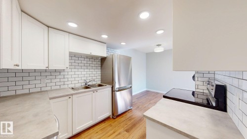 Kitchen with decorative backsplash, light countertops, white cabinets, light wood-style floors, and recessed lighting - 611 2908 116A Avenue, Edmonton, AB - Indoor Photo Showing Kitchen With Double Sink With Upgraded Kitchen