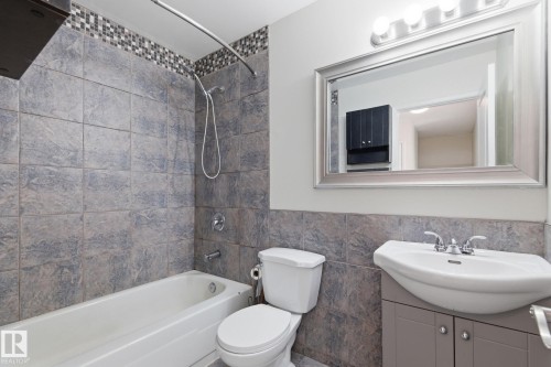 Bathroom featuring vanity, tub / shower combination, tile walls, and a wainscoted wall - 180 Londonderry Square, Edmonton, AB - Indoor Photo Showing Bathroom