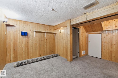 Unfurnished room with carpet, a textured ceiling, and wooden walls - 180 Londonderry Square, Edmonton, AB - Indoor