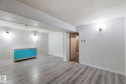 Spare room featuring wood walls, wood finished floors, and a textured ceiling - 180 Londonderry Square, Edmonton, AB - Indoor Photo Showing Other Room