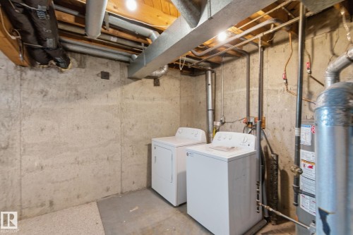 Laundry area with unfinished concrete floors, washing machine and clothes dryer, and gas water heater - 180 Londonderry Square, Edmonton, AB - Indoor