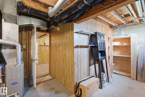 Unfinished basement featuring heating unit and wood walls - 180 Londonderry Square, Edmonton, AB - Indoor Photo Showing Basement