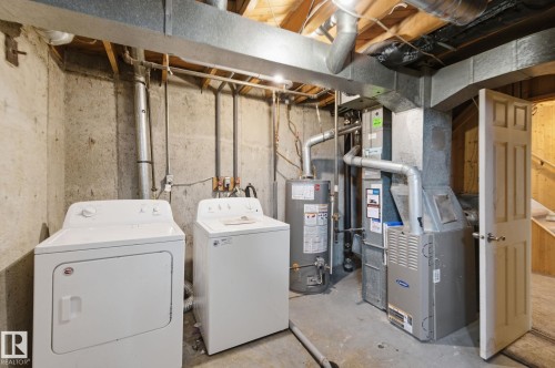 Laundry area with unfinished concrete floors, heating unit, water heater, and washing machine and dryer - 180 Londonderry Square, Edmonton, AB - Indoor Photo Showing Laundry Room