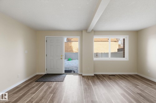 Foyer featuring beam ceiling, light wood-style flooring, healthy amount of natural light, and a textured ceiling - 180 Londonderry Square, Edmonton, AB - Indoor Photo Showing Other Room