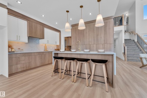 Kitchen featuring two tone cabinets, a kitchen bar, modern cabinets, light stone countertops, and a center island with sink - 228 Linden Loop, Leduc, AB - Indoor Photo Showing Kitchen With Upgraded Kitchen