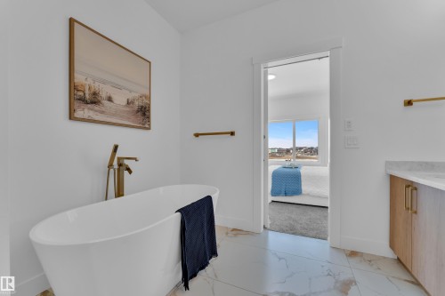 Full bath featuring light marble finish flooring, vanity, ensuite bath, and a freestanding tub - 228 Linden Loop, Leduc, AB - Indoor