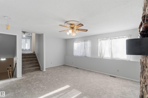 Unfurnished living room with a ceiling fan, carpet flooring, and a textured ceiling - 135 Humberstone Road, Edmonton, AB - Indoor Photo Showing Other Room