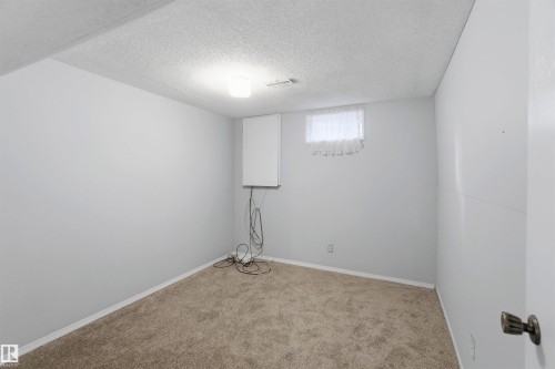 Carpeted spare room featuring a textured ceiling and baseboards - 135 Humberstone Road, Edmonton, AB - Indoor Photo Showing Other Room
