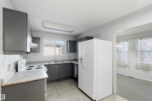 Kitchen featuring white appliances, gray cabinetry, light countertops, and light tile patterned floors - 135 Humberstone Road, Edmonton, AB - Indoor Photo Showing Kitchen