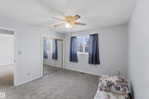 Carpeted bedroom with a ceiling fan, a textured ceiling, and a closet - 135 Humberstone Road, Edmonton, AB - Indoor