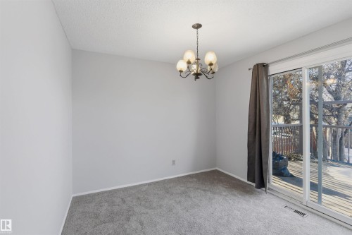 Carpeted spare room with hanging lights and a textured ceiling - 135 Humberstone Road, Edmonton, AB - Indoor Photo Showing Other Room