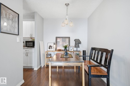 Dining space featuring dark wood finished floors, a textured ceiling, and suspended lighting - 1312 13910 Stony Plain Road, Edmonton, AB - Indoor