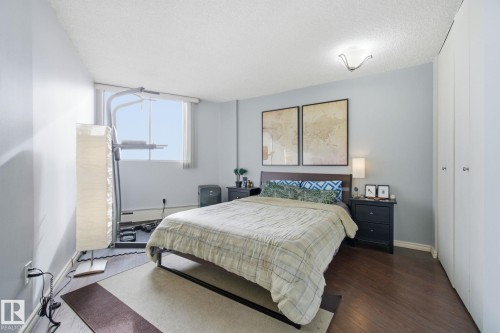 Bedroom with wood finished floors, a textured ceiling, and a baseboard radiator - 1312 13910 Stony Plain Road, Edmonton, AB - Indoor Photo Showing Bedroom