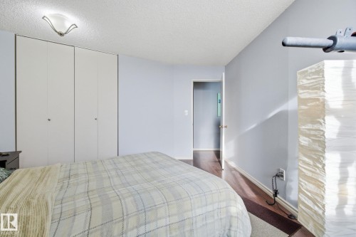 Bedroom with a textured ceiling, dark wood-type flooring, and a closet - 1312 13910 Stony Plain Road, Edmonton, AB - Indoor Photo Showing Bedroom
